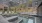 a pool with chairs and a building in the background